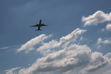 Fototapeta na wymiar Airplane flying over blue sky and clouds