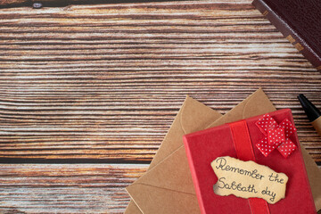 Remember Sabbath Day quote written on old paper on top of red gift box placed on wooden background...