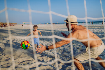 Fototapeta Father with his son plaing football on the beach. obraz
