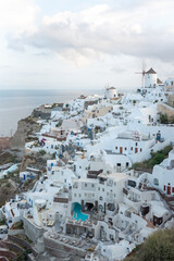Fototapeta na wymiar The view of Oia village at sunrise with white buildings and windmills in the background