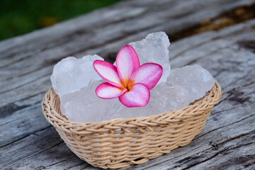 Soft focus of Alum cubes and plumeria flower on small wicker basket, blurred background, concept for herb, bodycare, skincare, waterclear, spa, treatment, disease protection and protect armpit smell.