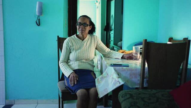 A thoughtful senior black woman sitting at apartment. A pensive hispanic latin south american senior person