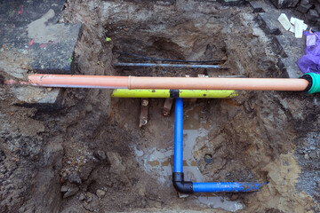 Blick auf einen freigelegten Wasseranschluss mit Ventilen, Rohren und Leitungen in einer Baugrube, Kanal