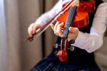 a girl in a beautiful white blouse with a frill and a blue skirt plays the violin, holds bows in her hands and plays music on a musical instrument © anastasiia