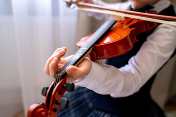 a girl in a beautiful white blouse with a frill and a blue skirt plays the violin, holds bows in her hands and plays music on a musical instrument