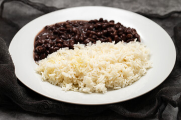 Black beans and boiled rice on white dish.