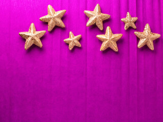 Border with big and small golden decorative stars on bright pink paper textured background. Top view. Christmas, New Year holidays concept.  Place for text.