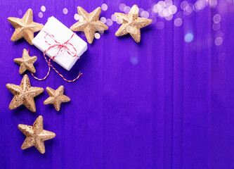 Border from wrapped boxes with presents  and golden decorative stars on violet paper  textured  background. Place for text. Flat lay. Holiday layout.
