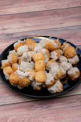 Fried Fish Tofu placed in a black plate and put on the wooden table.