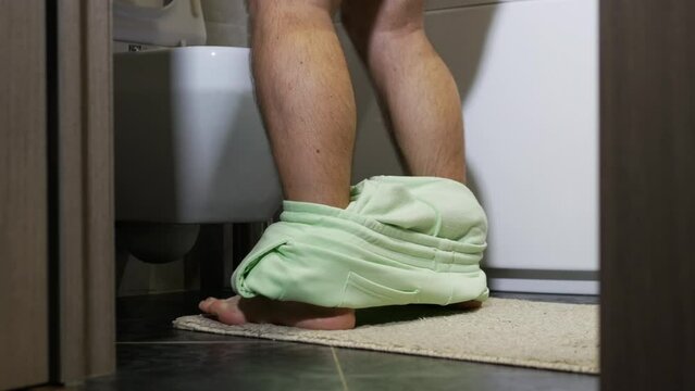Problems with prostate adenoma, frequent urination of a man man. Run to the toilet to eliminate the need. Disease of the genitourinary system. The man in the toilet pulls his pants down.