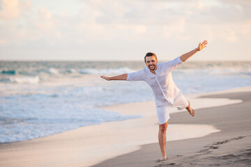 Young man in white on the beach having fun