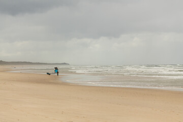 Fototapeta na wymiar Byron Bay shoreline in NSW during autumn season with person holding a sail, running along beach.