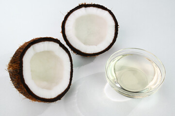 Coconut oil in a glass cup with split coconuts in the background.