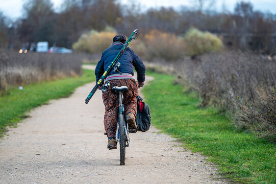 man with fishing gear on bicycle, back view