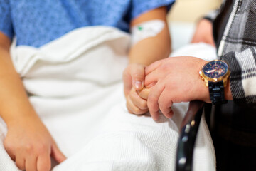 Sick woman about to undergo surgery holding her husband's hand
