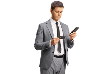 Young professional man holding a smartphone and looking at a credit card