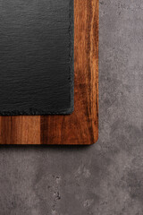 slate on wooden cutting board on dark marble background