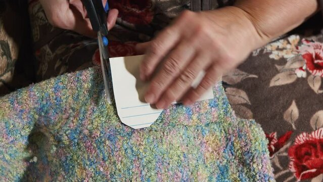 Grandma cuts out a template for New Year's socks with scissors. the active old age of the grandmother makes socks for her grandchildren with her own hands. hands of an elderly woman cutting out close-