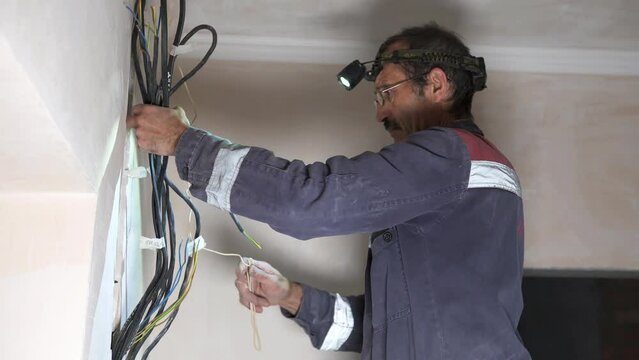 An electrician is laying a new wiring route in the apartment. Electrical panel installation and wire marking.