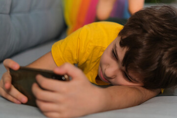 Obraz na płótnie Canvas sleepy boy playing on the phone lying on the couch. addiction to gadgets, overwork, apathy