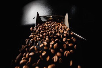 Macro Fresh roasted coffee beans move on professional mixing roaster machines, dark background