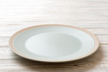 Perspective view of empty light plate on wooden background. Empty space for your design