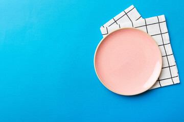 Top view on colored background empty round pink plate on tablecloth for food. Empty dish on napkin with space for your design