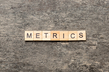 Fototapeta premium METRICS word written on wood block. METRICS text on cement table for your desing, concept