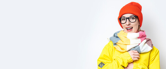 Smiling beautiful young woman in a hat, in a yellow jacket on a light background.