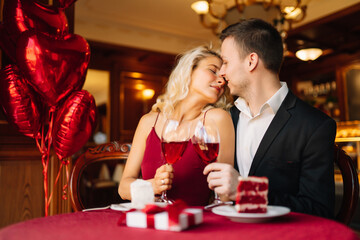Young couple having a romantic dinner and toasting with glass of red wine. Valentine's Day concept. Relationship, surprise and love concept.