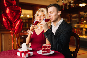 Young couple having a romantic dinner and toasting with glass of red wine. Valentine's Day concept. Relationship, surprise and love concept.