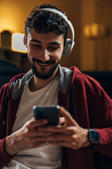 Young man smiles while looking at his smart phone