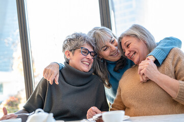 Three mature senior women friends having fun together, elder lifestyle of woman having breakfast on...