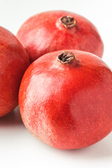 Fresh whole pomegranate fruits isolated on white background. Ripe pomegranates with glossy red peel