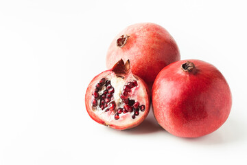 Whole and half of fresh pomegranate fruit isolated on white background. Ripe pomegranates cracked in a half with red juicy seeds exposed