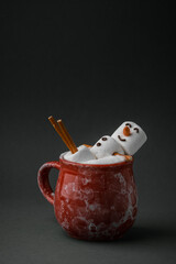 Marshmallow snowman taking hot tub in a red ceramic cup full of cocoa with milk foam. Christmas...