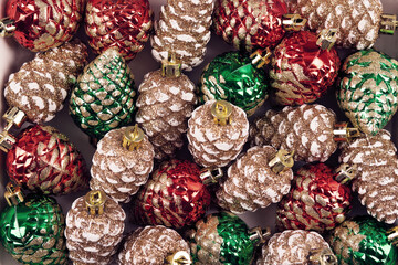 Abstract background of Christmas decorations in the form of pine cones in green, red and gold...
