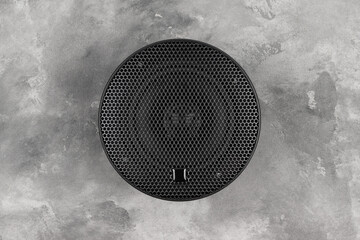 Stylish car audio acoustic round speaker with waffle grill protector cover on on gray concrete...