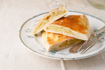 Traditional potato pie. Vintage plate, cutlery. Beige and textile background.