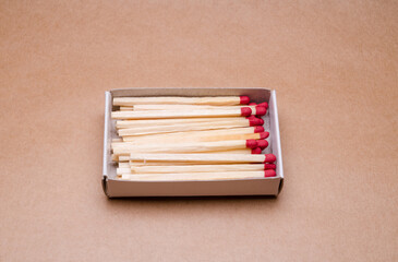 Set of new unlit matchsticks in a matchbox on natural brown paper background