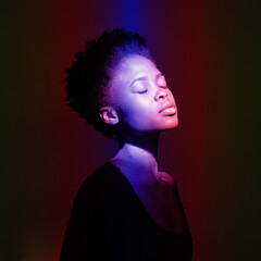 Young happy African woman in the studio. A female model in colorful bright neon lights poses on a...
