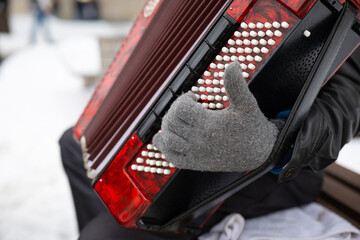A musician playing the accordion in winter gloves - obrazy, fototapety, plakaty