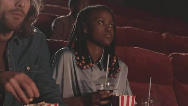 Young diverse people laughing while watching comedy film at cinema on weekend