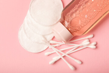 Micellar cleansing water, cotton buds,towel and cotton pads on a pink background, top view.Delicate cleansing everyday concept. Skin cleansing from cosmetics and sebium. Skin care concept.