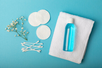 Micellar cleansing water, cotton buds,towel and cotton pads on a blue background, top view.Delicate cleansing everyday concept. Skin cleansing from cosmetics and sebium. Skin care concept.