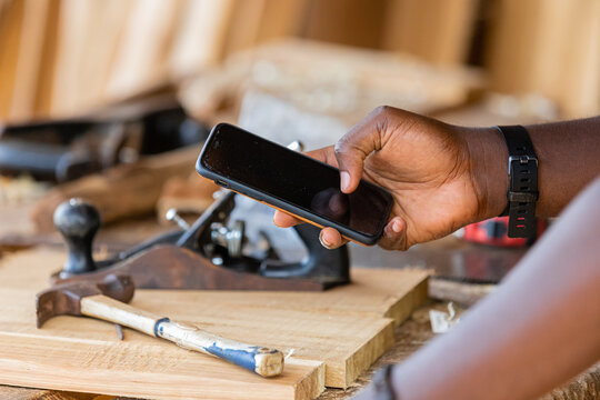 Close-up of a professional carpenter holding a mobile phone. taking measurements using an app on their smartphone
