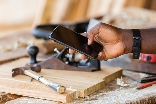 Close-up of a professional carpenter holding a mobile phone. taking measurements using an app on their smartphone