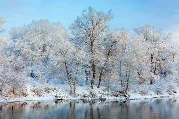 Peel and stick wall murals Reflection Beautiful view of the winter river and fishermen's bridges. Trees against the background of the morning blue sky. Snow-covered trees on the river bank are reflected in the water after snowfall.