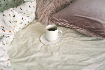 Fototapeta na wymiar Coffee on the bed in the room. Breakfast in a bed. Cozy morning.