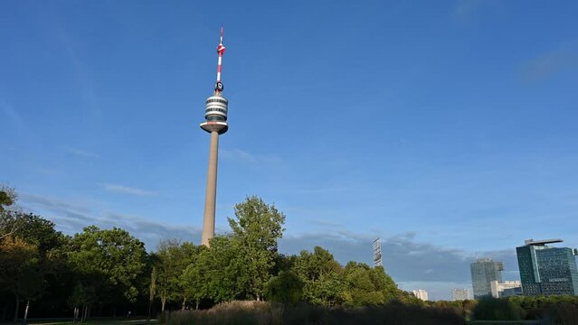 Vienna, Austria, August 2022. Panorama of Postwiese Donau Park. The pan movement starts from the Donauturm tower to move on to buildings in the uno city.